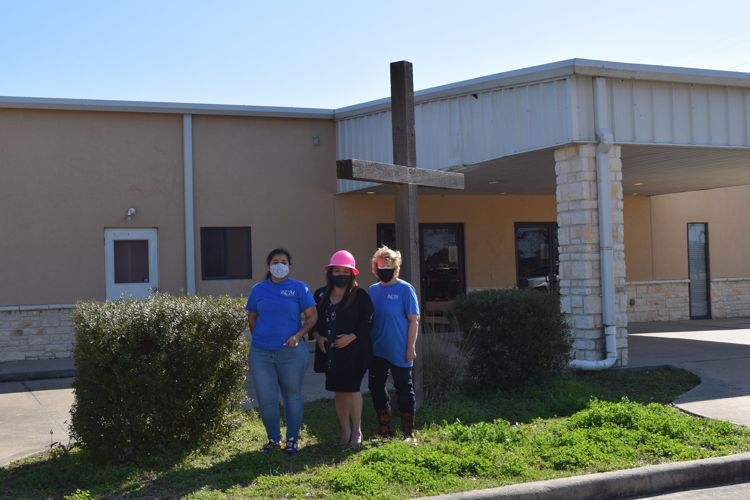 Katy Christian Ministries Executive Director Deysi Crespo (center in pink hardhat) poses with KCM Business Development Manager Jeannette Trejo (left) and KCM Master Gardener Karen Smith (right) in front of KCM’s new headquarters building at 3506 Porter Road in the Katy area. The new facility will allow the nonprofit to consolidate operations, enlarge its food pantry and enhance its community garden.
